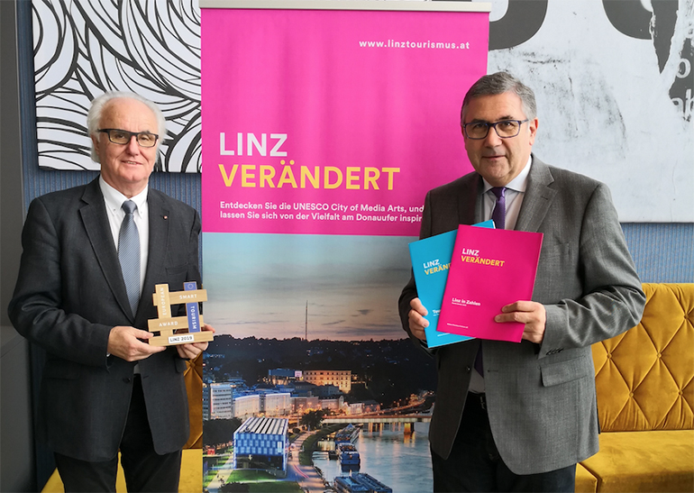 Manfred Grubauer, Vorsitzender des Tourismusverbandes Linz, (l.) mit dem EU-Award und Tourismusdirektor Georg Steiner freuen sich über den Nächtigungsrekord 2018