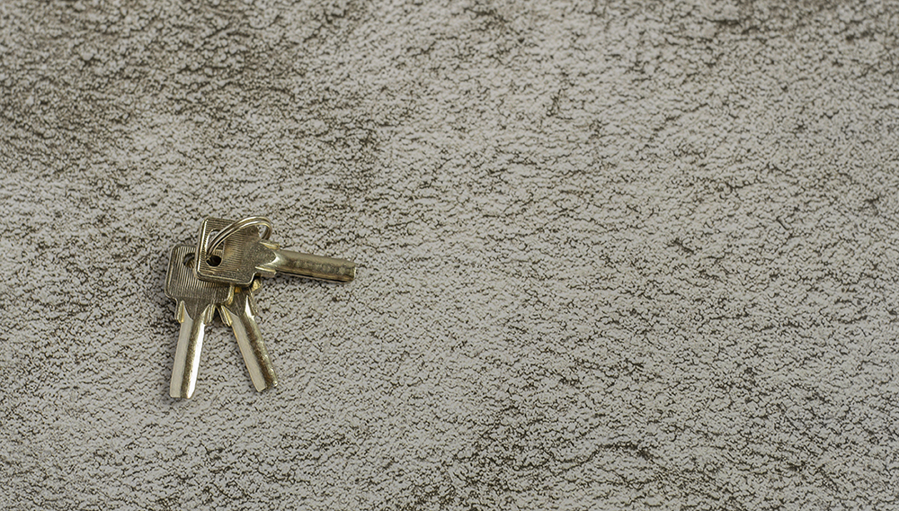 A bunch of three keys to the apartment is on a gray background with a copy of the space.