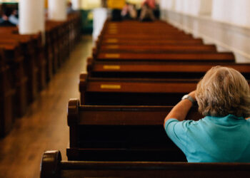 senior woman praying at a pew in church