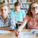 Serious girls sitting by desk and looking at blackboard at lesson